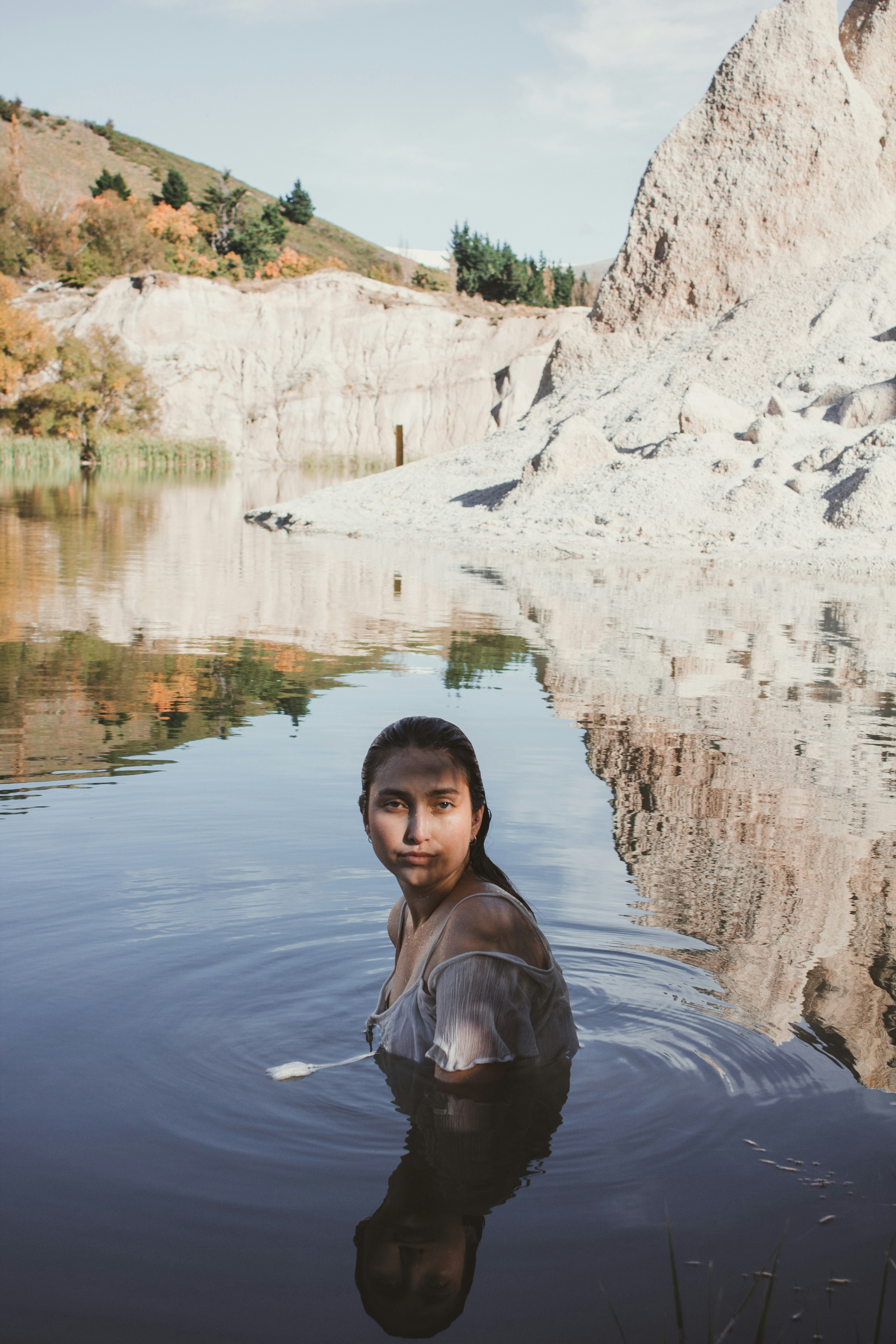 woman in body of water beside rocky mountain during daytime